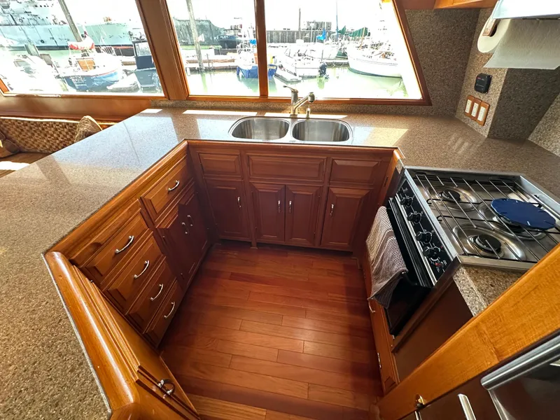 Slide: The Image of 1985 Ocean Alexander Pilothouse kitchen with wood cabinets, dual sink, and gas stove, overlooking marina. - 44