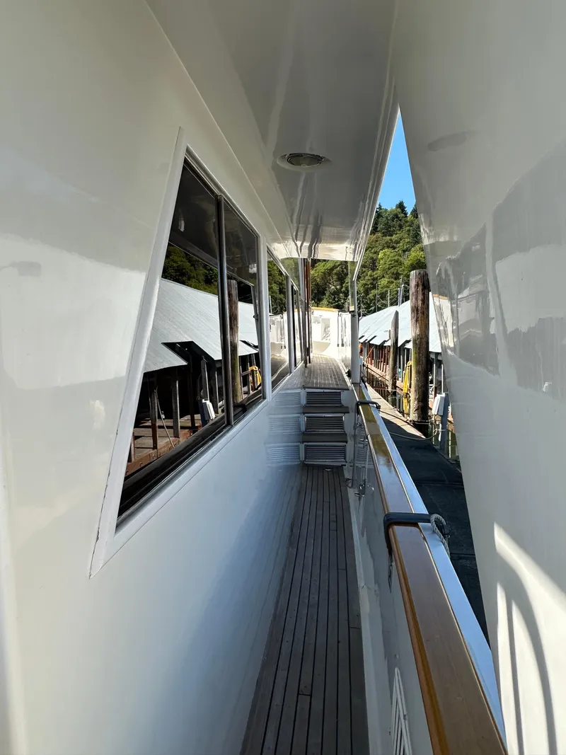 Slide: The Image of 1985 Ocean Alexander Pilothouse yacht deck with wooden flooring and sleek white exterior. - 7