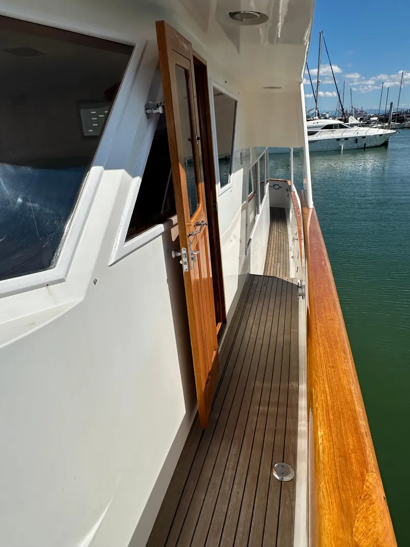Slide: The Image of 1985 Ocean Alexander Pilothouse yacht with wooden deck and open door, docked in marina. - 8