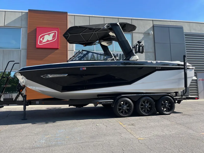 The Image of 2022 Nautique Super Air G23 boat on trailer, parked outside a building. - 1