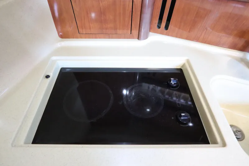 Slide: The Image of Stovetop in 2004 Sea Ray 420 Sundancer yacht kitchen, featuring sleek black surface and control knobs. - 31