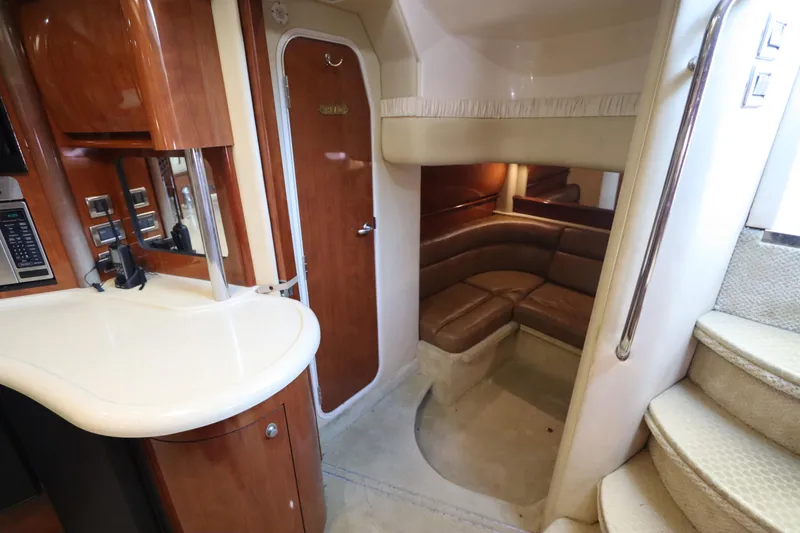 Slide: The Image of 2004 Sea Ray 420 Sundancer interior with curved seating, wooden cabinetry, and stairs. - 45