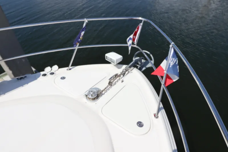 Slide: The Image of Bow of 2004 Sea Ray 420 Sundancer with flags and anchor chain on calm water. - 7