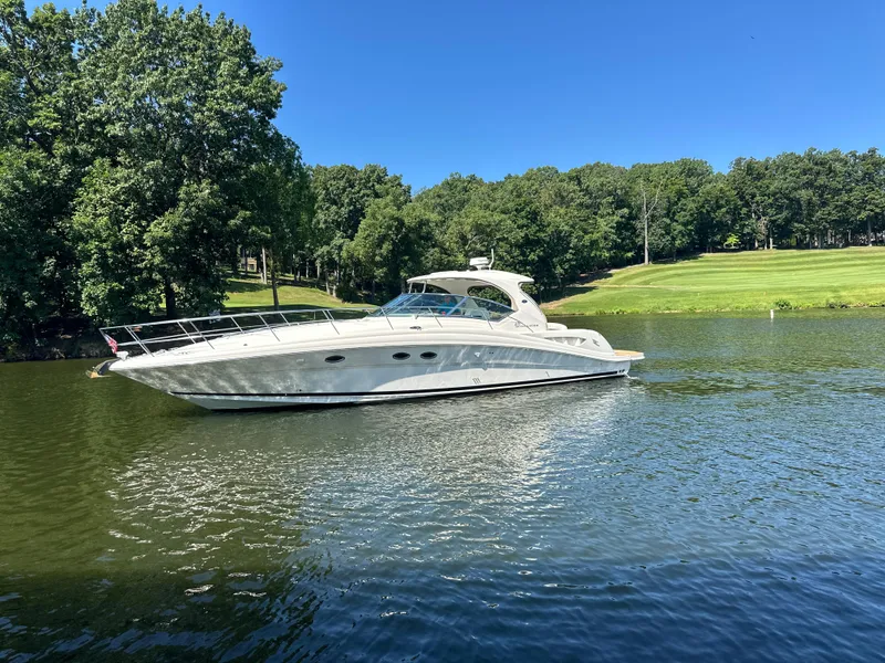 Slide: The Image of 2005 Sea Ray 420 Sundancer yacht on a serene lake with lush green trees. - 10