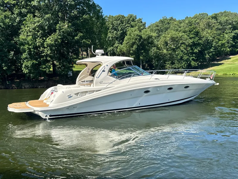 Slide: The Image of 2005 Sea Ray 420 Sundancer yacht cruising on a serene lake with lush green trees. - 2