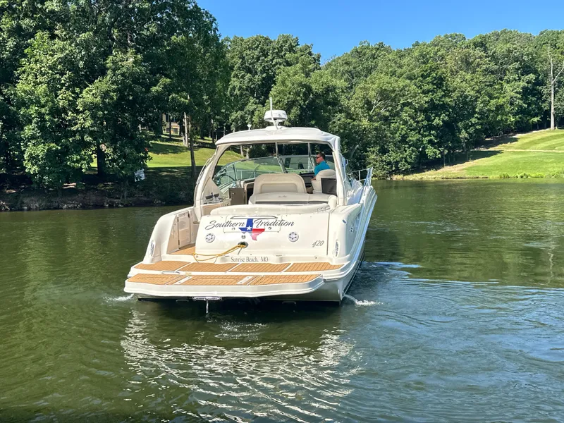 Slide: The Image of 2005 Sea Ray 420 Sundancer cruising on a serene lake with lush green surroundings. - 4