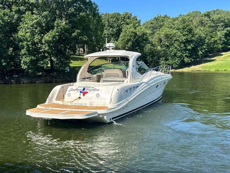 Slide: The Image of 2005 Sea Ray 420 Sundancer yacht cruising on a serene lake with lush green trees. - 7