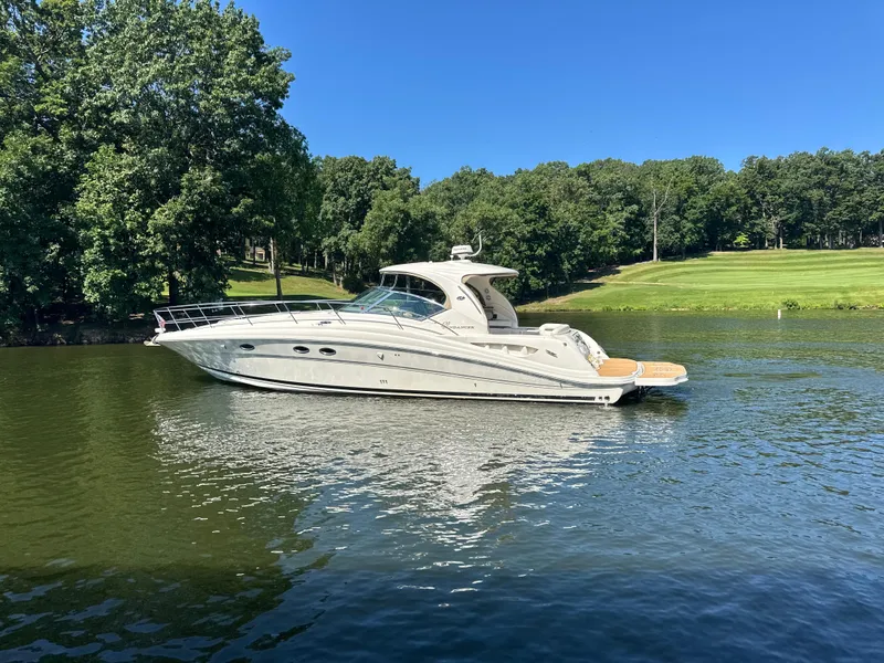 Slide: The Image of 2005 Sea Ray 420 Sundancer yacht on a serene lake with lush green surroundings. - 8