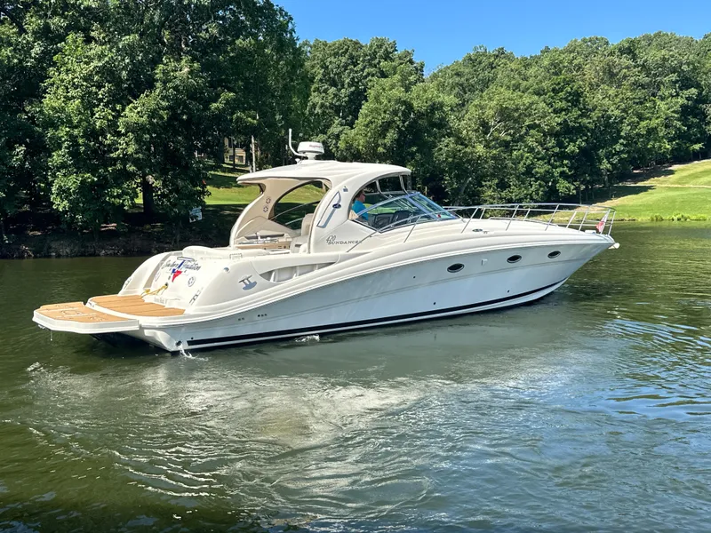 Slide: The Image of 2005 Sea Ray 420 Sundancer yacht cruising on a serene lake with lush green trees. - 9