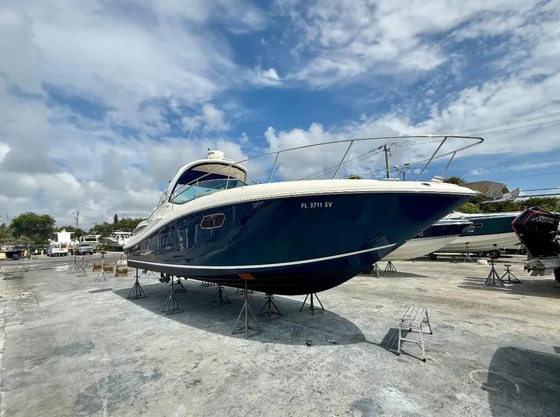 The Image of 2011 Sea Ray 350 Sundancer boat on dry dock under a partly cloudy sky. - 0