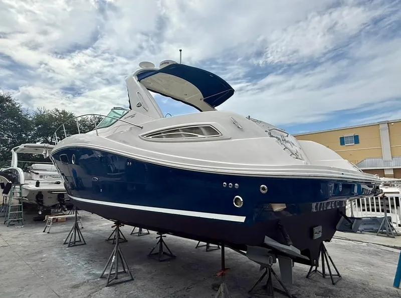 Slide: The Image of 2011 Sea Ray 350 Sundancer yacht on stands, blue and white exterior, under a cloudy sky. - 4