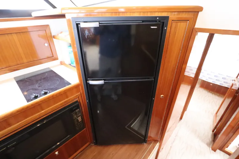 Slide: The Image of The 2001 Riviera 43 Open Flybridge galley features a black fridge, stove, and microwave. - 44