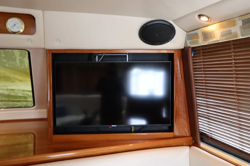 Slide: The Image of A television is mounted in a wooden frame on a boat's wall. Speakers and blinds are visible nearby. - 37