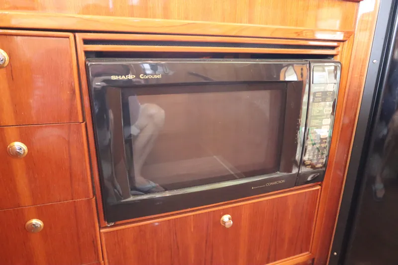 Slide: The Image of A built-in microwave in a wooden cabinet on a 2001 Riviera 43 Open Flybridge. - 43