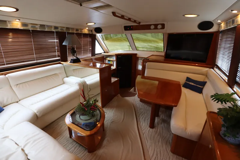 Slide: The Image of The image shows the luxurious interior of a 2001 Riviera 43 Open Flybridge with white leather sofas and wooden tables. - 29