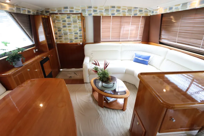 Slide: The Image of The interior of a 2001 Riviera 43 Open Flybridge features an elegant, bright seating area with a wooden table. - 31
