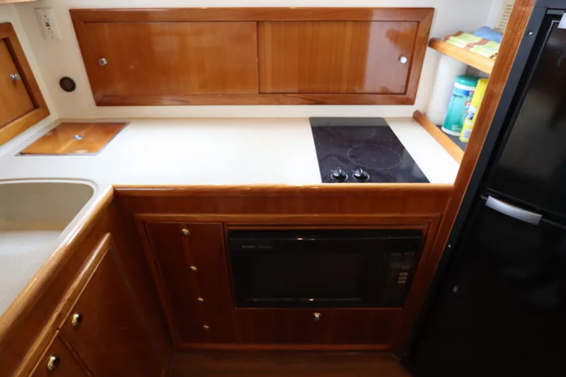 Slide: The Image of The galley of a 2001 Riviera 43 Open Flybridge with wooden cabinets, stove, and microwave. - 41