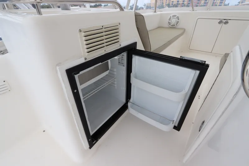 Slide: The Image of An open refrigerator on a boat with white walls and a beige seating area. - 21