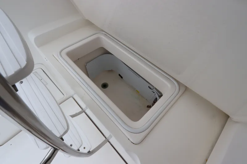 Slide: The Image of An open storage compartment on a boat with a white interior and a drain hole. - 16