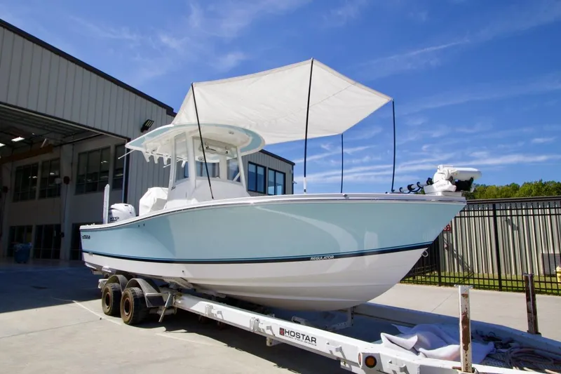 Slide: The Image of 2026 Regulator 26XO boat interior with white seating, docked near a modern building. - 10