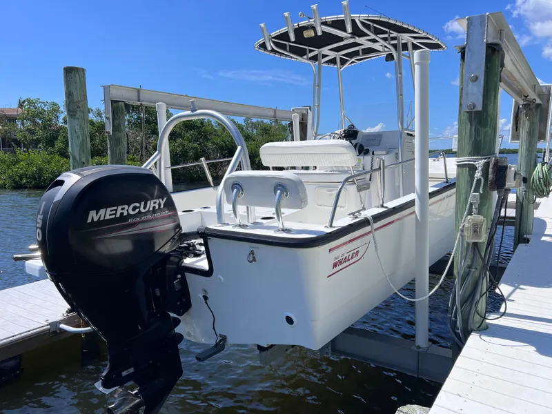 Slide: The Image of 2016 Boston Whaler 210 Montauk boat with Mercury outboard engine docked by the water. - 2
