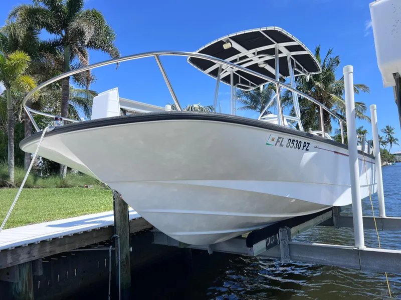 Slide: The Image of 2016 Boston Whaler 210 Montauk boat on lift, surrounded by palm trees and water. - 5