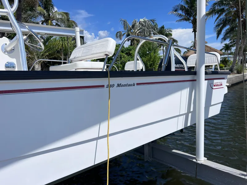 Slide: The Image of 2016 Boston Whaler 210 Montauk boat docked near palm trees under blue sky. - 6