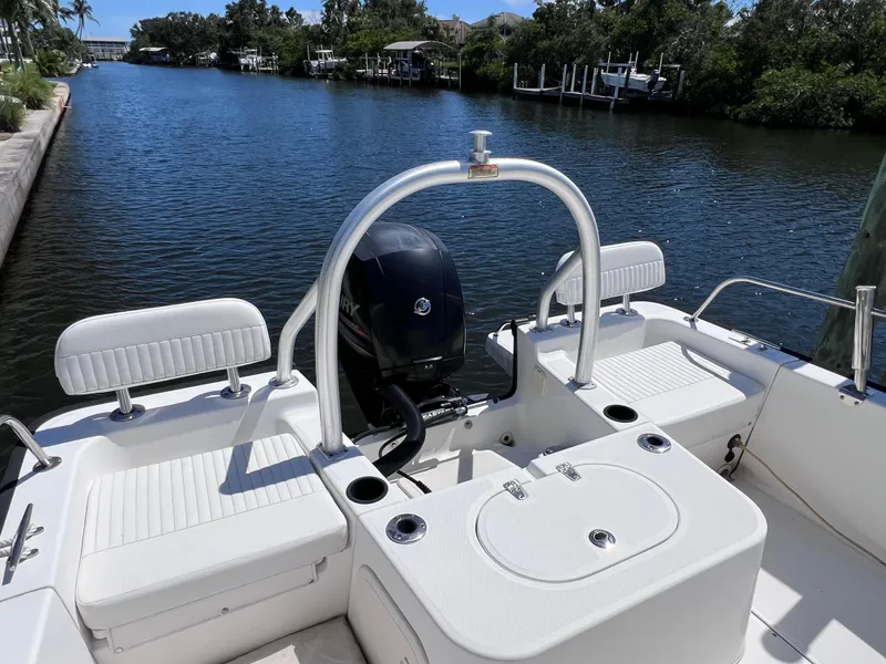 Slide: The Image of 2016 Boston Whaler 210 Montauk boat interior with seating and motor, docked on a calm waterway. - 9