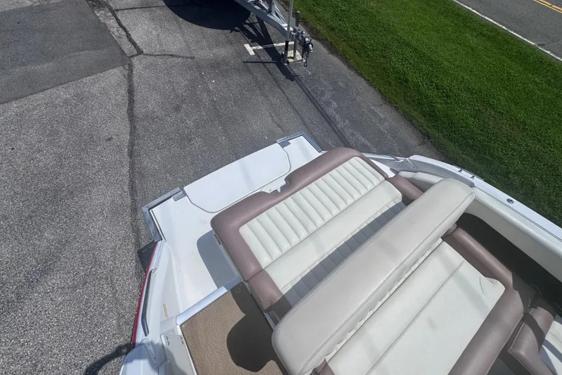 Slide: The Image of 2013 Cobalt 24SD boat with beige and white seating, parked on pavement. - 10