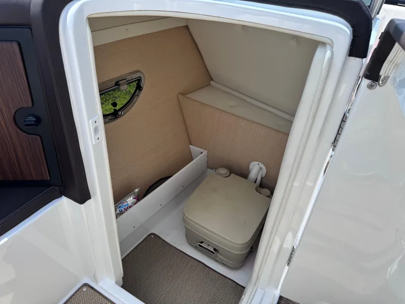 Slide: The Image of 2013 Cobalt 24SD boat interior with compact toilet and storage area. - 11