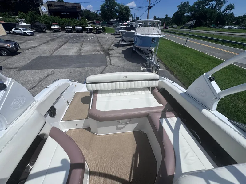 Slide: The Image of 2013 Cobalt 24SD boat interior with beige and white seating, parked outdoors. - 12