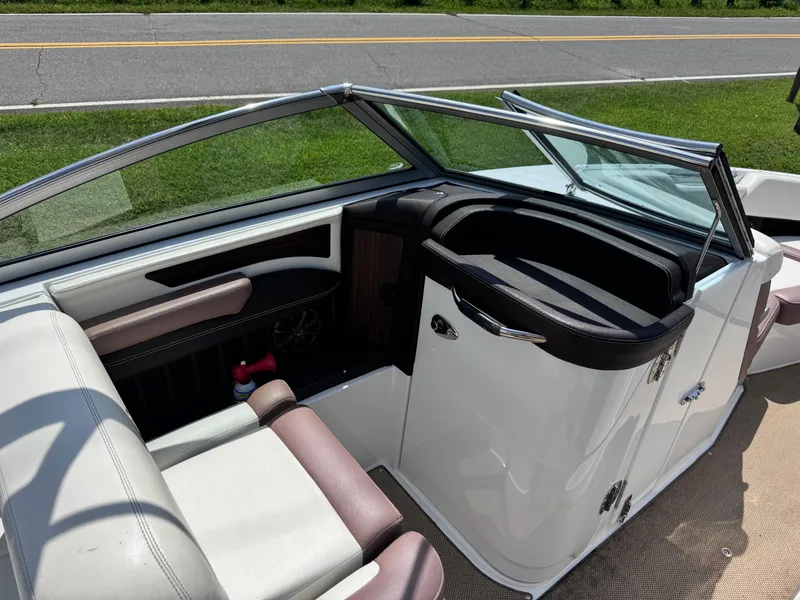 Slide: The Image of 2013 Cobalt 24SD boat interior with seating and storage, parked near a road. - 18
