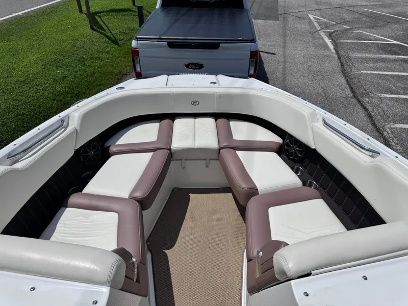 Slide: The Image of 2013 Cobalt 24SD boat interior with white and brown seating, parked near a Ford truck. - 24