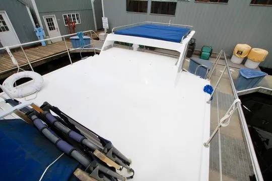 Slide: The Image of 2006 Harbor Master Coastal 400 boat docked, featuring spacious deck and blue canopy. - 23