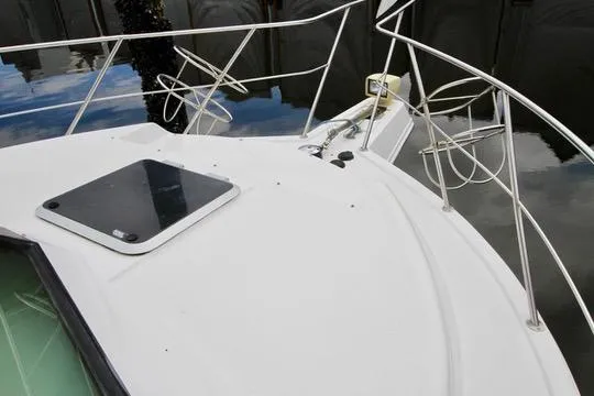 Slide: The Image of 2006 Harbor Master Coastal 400 boat deck with railing and hatch, docked on calm water. - 24