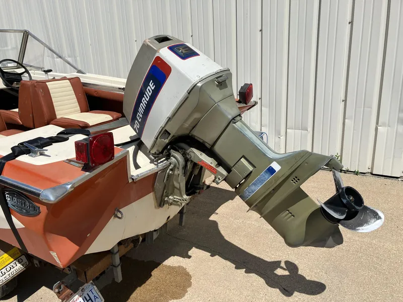 Slide: The Image of 1976 Glastron 156 Open Bow boat with Evinrude outboard motor, parked near a white wall. - 21