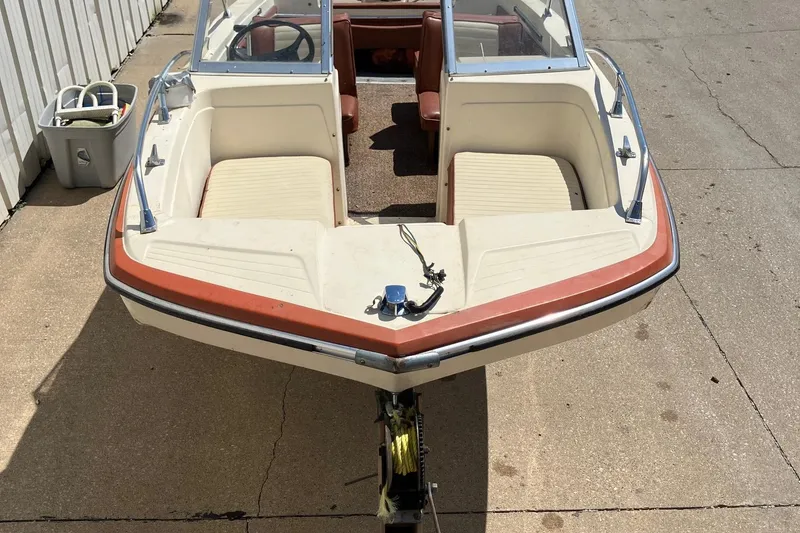 Slide: The Image of 1976 Glastron 156 Open Bow boat with beige and orange seating, parked on concrete. - 5