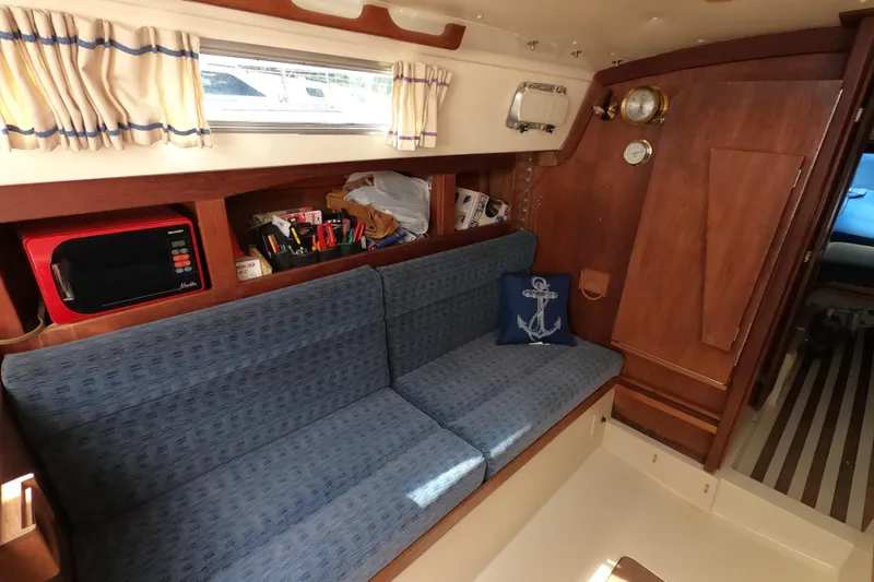 Slide: The Image of Interior of 1984 CAL 31 sailboat with blue seating, nautical decor, and wooden cabinetry. - 14