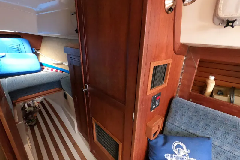 Slide: The Image of Interior of 1984 CAL 31 sailboat with wooden cabinetry and blue seating. - 16