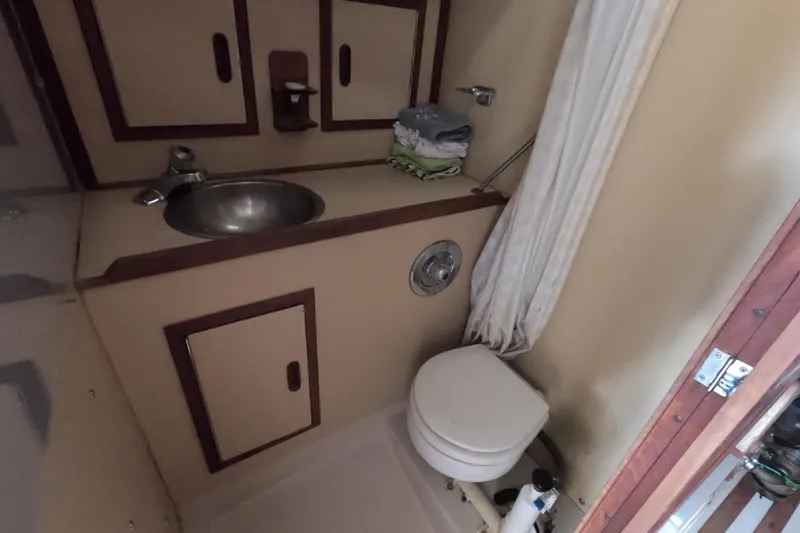 Slide: The Image of Compact bathroom in a 1984 CAL 31 sailboat with sink, toilet, and storage cabinets. - 17