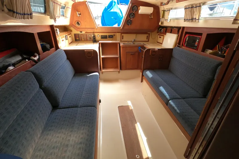 Slide: The Image of Interior of a 1984 CAL 31 sailboat with blue seating and wooden cabinetry. - 19
