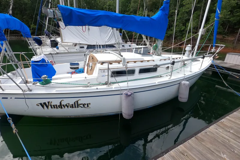 Slide: The Image of 1984 CAL 31 sailboat "Windwalker" docked, featuring blue covers and white hull. - 2