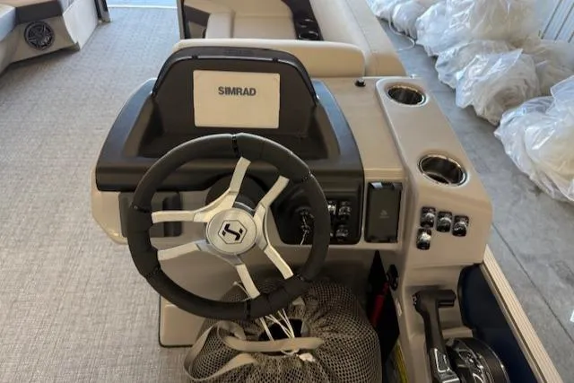 Slide: The Image of 2025 Harris Cruiser 230 CWDH boat dashboard with steering wheel and Simrad display. - 16