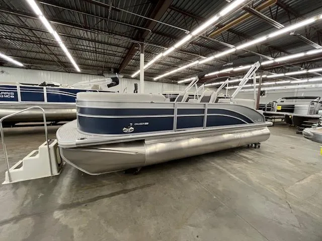The Image of 2025 Harris Cruiser 210 pontoon boat in a showroom, featuring sleek design and modern amenities. - 0