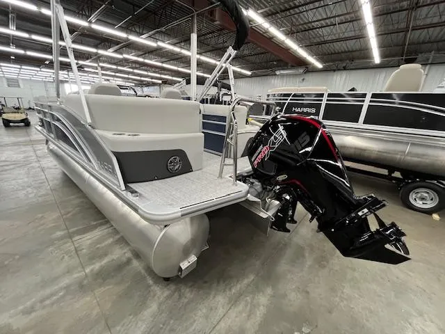 Slide: The Image of 2025 Harris Cruiser 210 pontoon boat with powerful outboard motor in a showroom. - 21