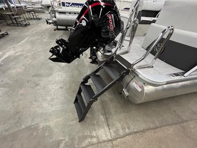 Slide: The Image of 2025 Harris Cruiser 210 boat with motor and boarding ladder in a showroom. - 23