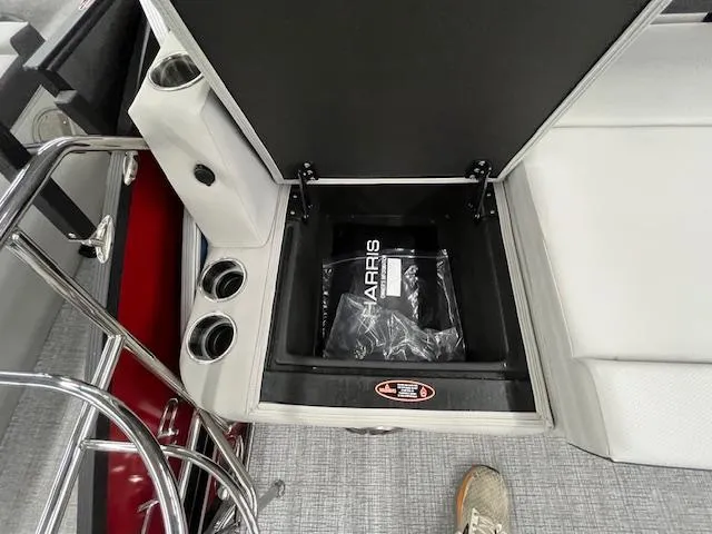 Slide: The Image of 2025 Harris Cruiser 210 boat storage compartment with cup holders and branded bag. - 11