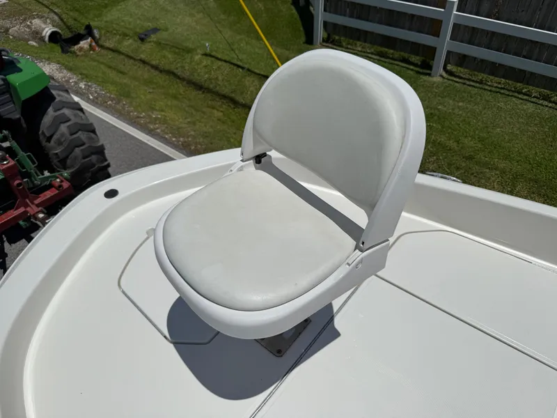 Slide: The Image of White seat on 2020 Bayliner Element F21 boat deck, with grass and tractor in background. - 19
