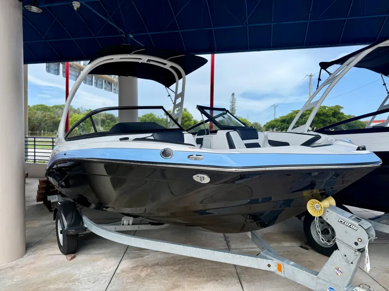 The Image of 2025 Yamaha Boats 195S on trailer, under blue canopy, sleek black and white design. - 0