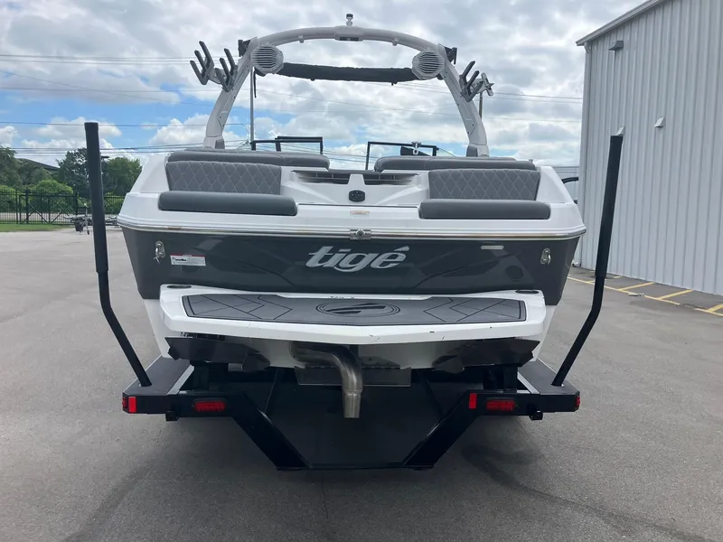 Slide: The Image of 2023 Tigé Z1 boat rear view, parked outdoors near a metal building. - 3